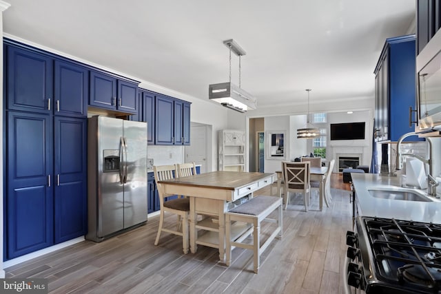 3960 Mountain View Ave, Easton, PA 18045 - kitchen with appliances with stainless steel finishes, blue cabinetry, light wood-style flooring, a fireplace, and decorative light fixtures