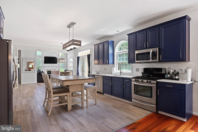3960 Mountain View Ave, Easton, PA 18045 - kitchen featuring appliances with stainless steel finishes, blue cabinets, decorative backsplash, light wood-style floors, and ornamental molding