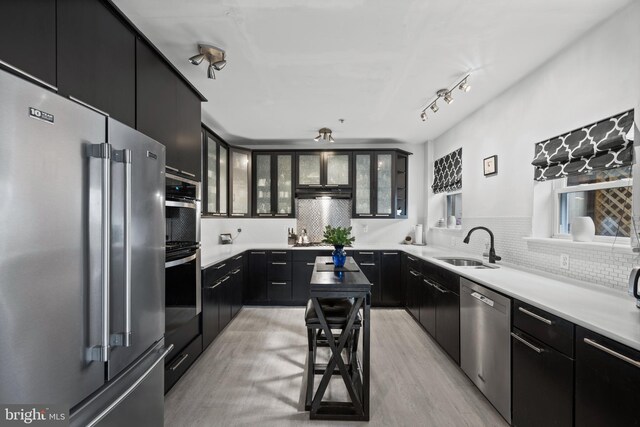 210 S High St, Baltimore, MD 21202 - kitchen featuring stainless steel appliances, dark cabinets, backsplash, and glass insert cabinets