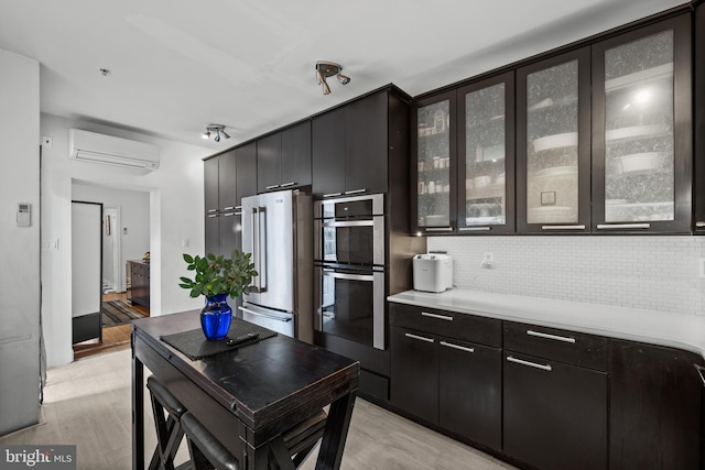 210 S High St, Baltimore, MD 21202 - kitchen featuring stainless steel appliances, an AC wall unit, light countertops, light wood-type flooring, and backsplash