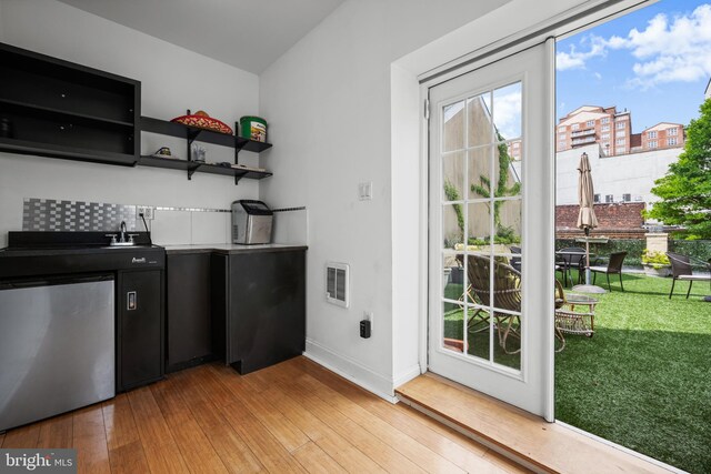 210 S High St, Baltimore, MD 21202 - kitchen featuring dark cabinetry, light wood-style floors, fridge, and open shelves