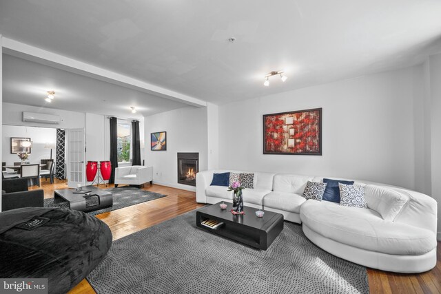 210 S High St, Baltimore, MD 21202 - living area featuring a wall mounted AC, wood finished floors, and a lit fireplace
