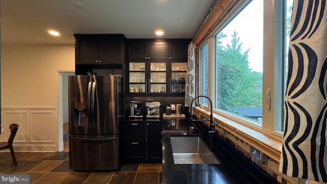 4309 Walther Ave, Baltimore, MD 21214 - kitchen featuring stainless steel refrigerator with ice dispenser, plenty of natural light, dark cabinets, dark stone finish flooring, and a wainscoted wall