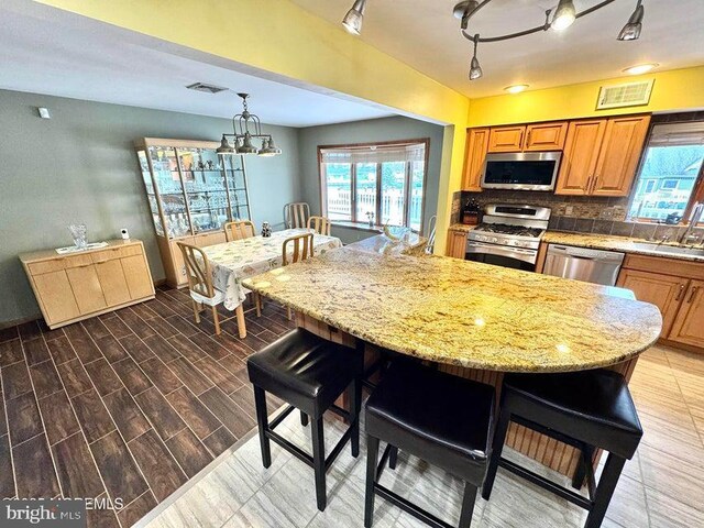 953 Capstan Dr, Forked River, NJ 08731 - kitchen with stainless steel appliances, a kitchen bar, plenty of natural light, and brown cabinetry
