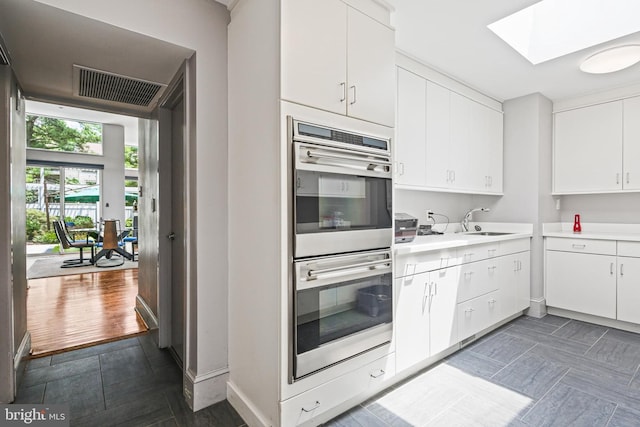 1 Regency Ct Unit 1, Baltimore, MD 21208 - kitchen with stainless steel double oven, light countertops, a skylight, and white cabinets