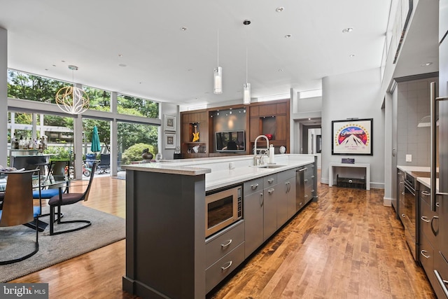 1 Regency Ct Unit 1, Baltimore, MD 21208 - kitchen with appliances with stainless steel finishes, hanging light fixtures, a large island with sink, and light wood-style flooring
