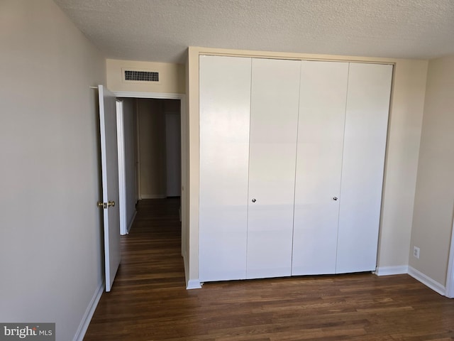 1101 Saint Paul St Unit 1212, Baltimore, MD 21202 - unfurnished bedroom featuring dark wood-style floors, a closet, and a textured ceiling