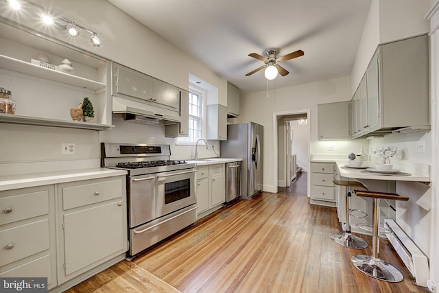 4110 Ingomar St NW, Washington, DC 20015 - kitchen with appliances with stainless steel finishes, under cabinet range hood, gray cabinets, baseboard heating, and ceiling fan