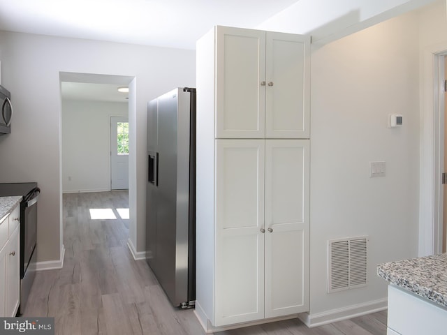 2450 Happy Creek Rd, Front Royal, VA 22630 - kitchen featuring appliances with stainless steel finishes, light stone countertops, light wood-style floors, and white cabinets