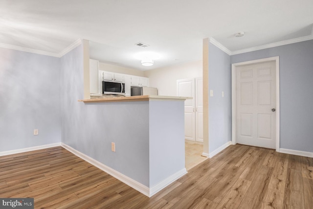 20406 Shore Harbour Dr Unit 4-A, Germantown, MD 20874 - kitchen with appliances with stainless steel finishes, ornamental molding, light wood-type flooring, white cabinets, and a peninsula