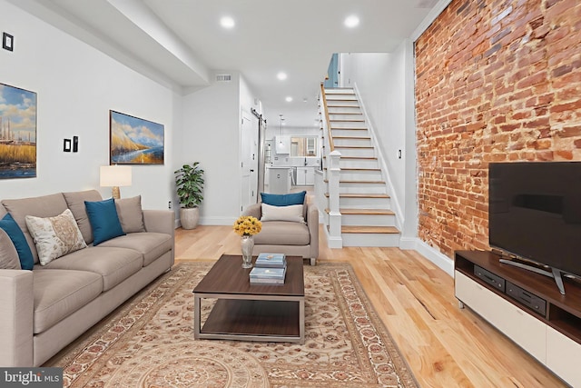 2002 E Lafayette Ave, Baltimore, MD 21213 - living room featuring a barn door, stairs, wood finished floors, recessed lighting, and brick wall