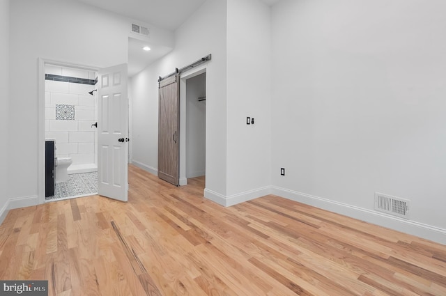 2002 E Lafayette Ave, Baltimore, MD 21213 - unfurnished bedroom featuring light wood-type flooring, a barn door, a spacious closet, a closet, and ensuite bath