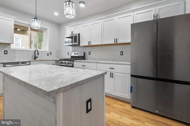 2002 E Lafayette Ave, Baltimore, MD 21213 - kitchen featuring appliances with stainless steel finishes, light wood finished floors, white cabinets, hanging light fixtures, and light stone countertops