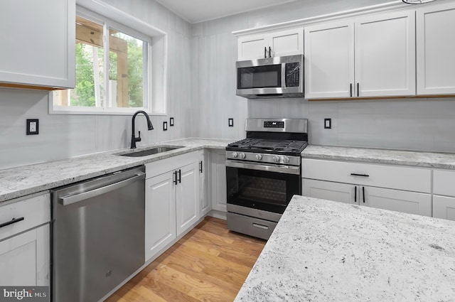 2002 E Lafayette Ave, Baltimore, MD 21213 - kitchen with stainless steel appliances, white cabinets, light wood-type flooring, and light stone countertops
