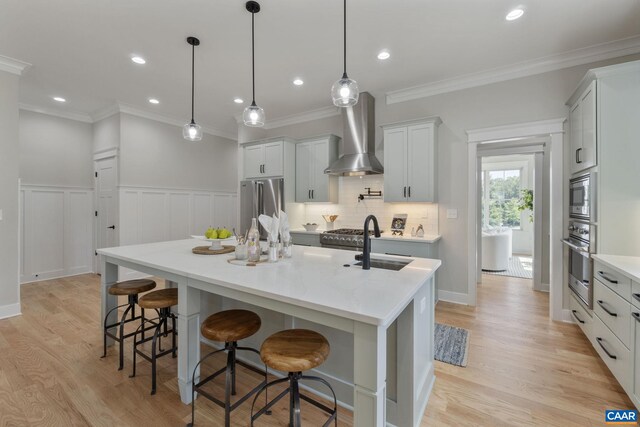1603 Griffen Grv, Charlottesville, VA 22901 - kitchen featuring wall chimney range hood, appliances with stainless steel finishes, an island with sink, a breakfast bar area, and crown molding