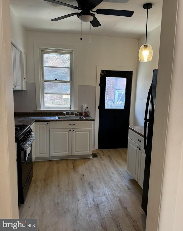 3433 E St, Philadelphia, PA 19134 - kitchen featuring black gas range oven, dark countertops, light wood-style floors, and white cabinets