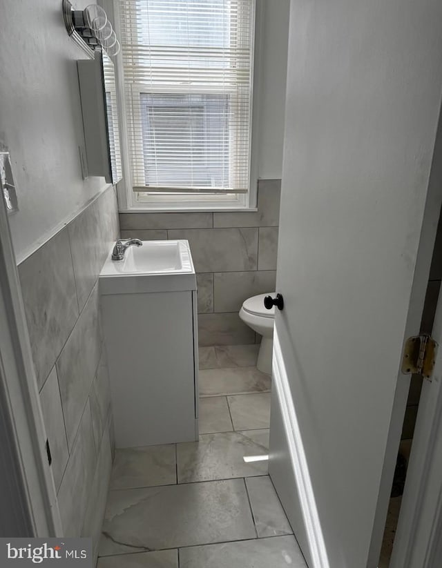 3433 E St, Philadelphia, PA 19134 - half bathroom with tile walls, vanity, marble finish flooring, and a wainscoted wall