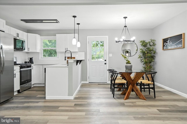 1415 Larch Rd, Severn, MD 21144 - kitchen featuring stainless steel appliances, white cabinetry, light wood-type flooring, a peninsula, and hanging light fixtures