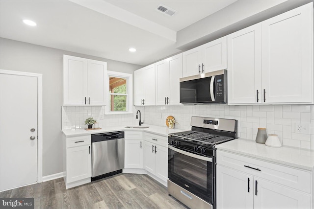 3912 Fernhill Ave, Baltimore, MD 21215 - kitchen with stainless steel appliances, light wood-style floors, white cabinets, decorative backsplash, and recessed lighting