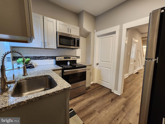 335 N 60th St, Philadelphia, PA 19139 - kitchen with appliances with stainless steel finishes, backsplash, light stone countertops, dark wood finished floors, and white cabinets