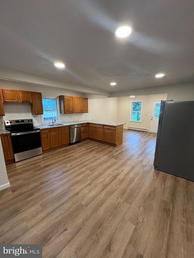 5825 Ebenezer Rd, White Marsh, MD 21162 - kitchen featuring stainless steel appliances, brown cabinets, light wood-style floors, a peninsula, and plenty of natural light