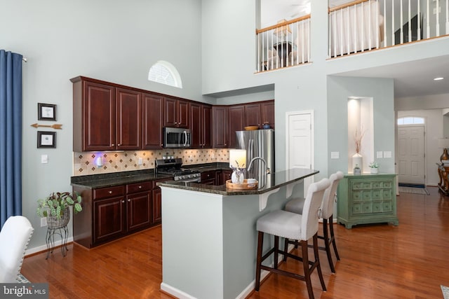 42 Ruddy Duck Ln, Bridgeville, DE 19933 - kitchen featuring stainless steel appliances, a towering ceiling, decorative backsplash, a kitchen bar, and wood finished floors