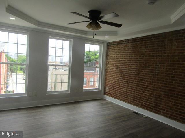16 Gilmor St, Baltimore, MD 21223 - spare room with a tray ceiling, brick wall, a ceiling fan, dark wood-style floors, and crown molding