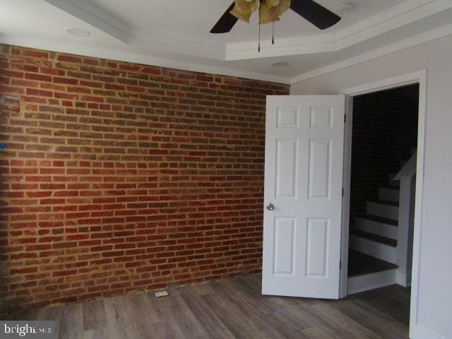16 Gilmor St, Baltimore, MD 21223 - spare room with crown molding, brick wall, ceiling fan, dark wood-style floors, and a raised ceiling