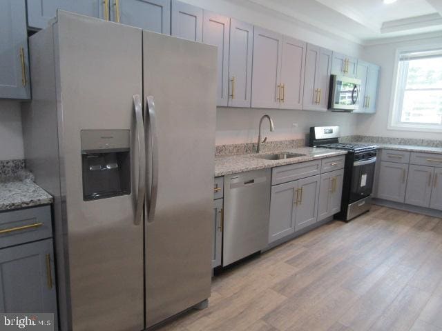 16 Gilmor St, Baltimore, MD 21223 - kitchen with stainless steel appliances, light wood finished floors, a raised ceiling, and gray cabinets