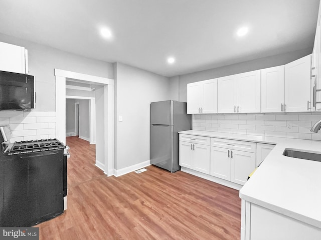 534 Columbia Ave, Millville, NJ 08332 - kitchen with gas range oven, black microwave, freestanding refrigerator, decorative backsplash, and light countertops