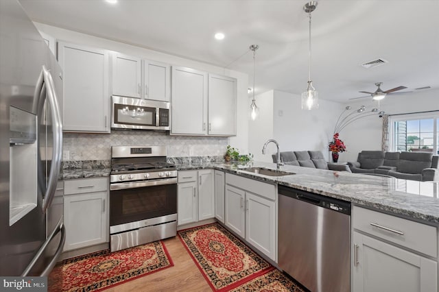 200 Harvin Way Unit 231, Brookhaven, PA 19015 - kitchen with stainless steel appliances, open floor plan, decorative backsplash, light stone counters, and light wood-style flooring