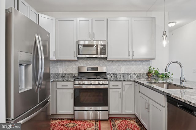 200 Harvin Way Unit 231, Brookhaven, PA 19015 - kitchen featuring appliances with stainless steel finishes, light stone counters, decorative backsplash, and hanging light fixtures