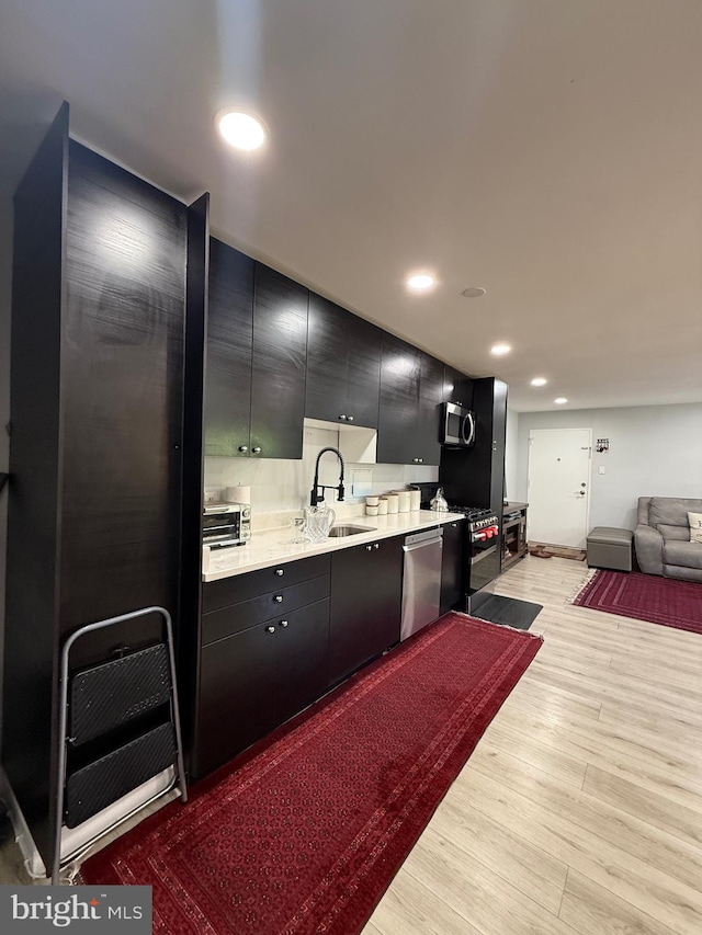 12656 Dara Dr, Woodbridge, VA 22192 - kitchen featuring appliances with stainless steel finishes, dark cabinets, light countertops, light wood-type flooring, and recessed lighting