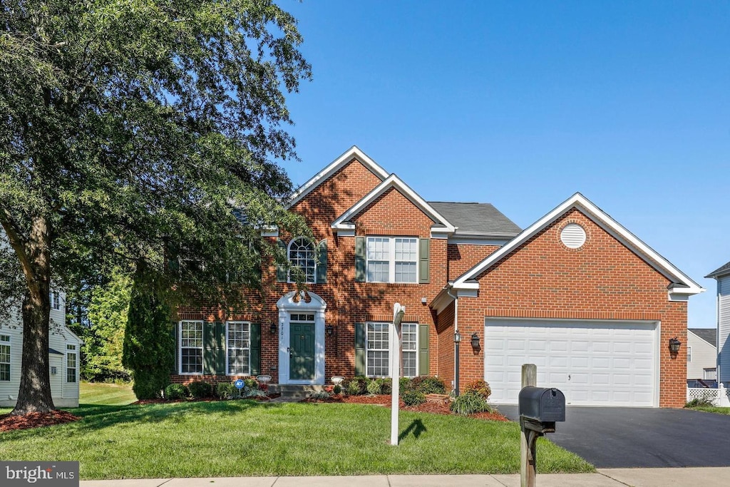 2701 Myrtlewood Dr, Dumfries, VA 22026 - colonial-style house featuring driveway, brick siding, a front yard, and an attached garage