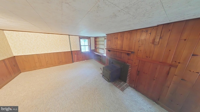 899 Shrivers Corner Rd, Gettysburg, PA 17325 - unfurnished living room with wooden walls, carpet, a wood stove, and wainscoting