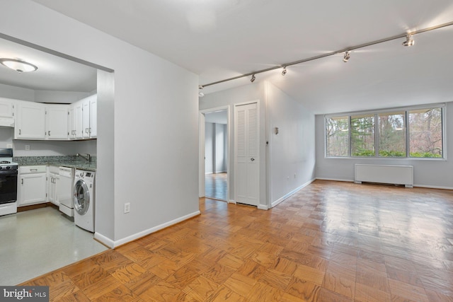 2939 Van Ness St NW Unit 230, Washington, DC 20008 - kitchen with washer / clothes dryer, radiator, range with electric stovetop, track lighting, and white cabinets