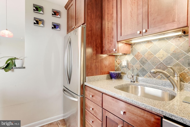 2501 Calvert St NW Unit 701, Washington, DC 20008 - kitchen with freestanding refrigerator, tasteful backsplash, light stone counters, hanging light fixtures, and brown cabinetry
