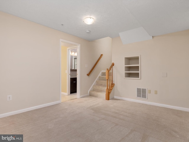 8730 Thornbrook Dr, Odenton, MD 21113 - empty room featuring light carpet, stairs, built in shelves, a textured ceiling, and a smoke detector