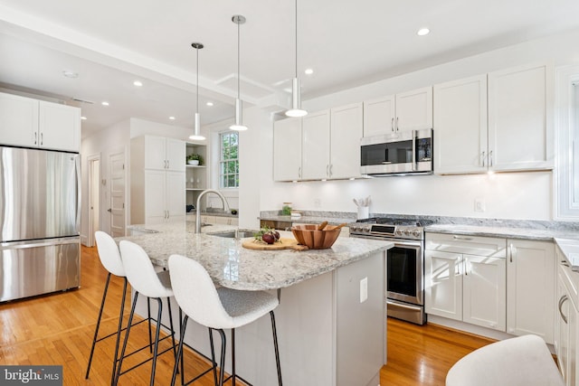 3518 35th St NW, Washington, DC 20016 - kitchen with stainless steel appliances, white cabinets, an island with sink, light wood-style flooring, and recessed lighting
