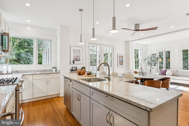 3518 35th St NW, Washington, DC 20016 - kitchen with stainless steel appliances, open floor plan, light stone countertops, a ceiling fan, and a center island with sink