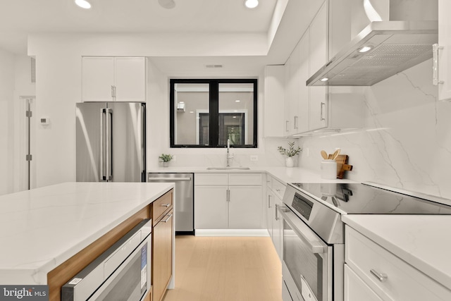 507 L St NE Unit 3B, Washington, DC 20002 - kitchen featuring wall chimney range hood, stainless steel appliances, recessed lighting, white cabinets, and decorative backsplash