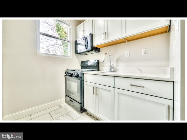 1206 Darley Ave, Baltimore, MD 21218 - kitchen featuring black appliances, light marble finish floors, and white cabinetry