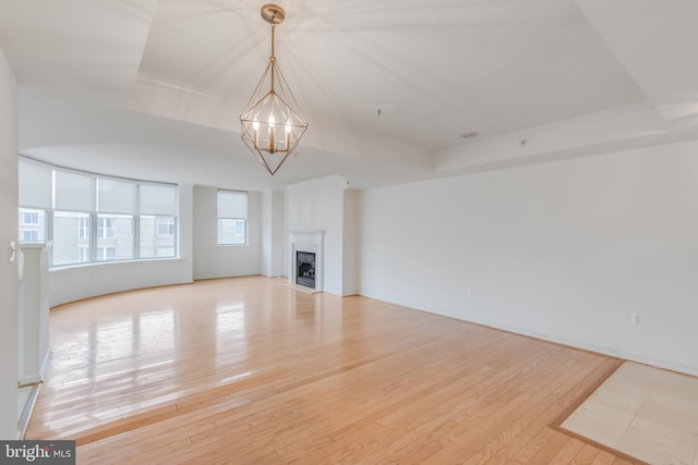 3835 9th St N Unit 1001W, Arlington, VA 22203 - unfurnished living room featuring a chandelier, light wood finished floors, a fireplace, and a tray ceiling