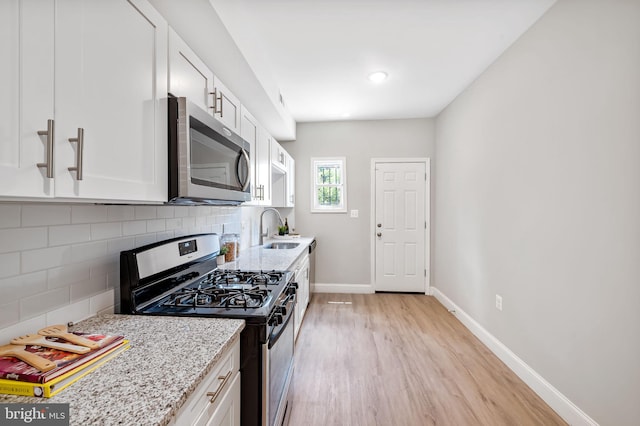 1607 Clifton Ave, Baltimore, MD 21217 - kitchen featuring stainless steel appliances, light wood-type flooring, white cabinetry, and light stone countertops