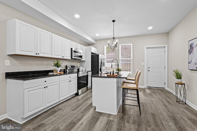 2328 E Hoffman St, Baltimore, MD 21213 - kitchen with stainless steel appliances, wood finished floors, a kitchen bar, white cabinetry, and recessed lighting