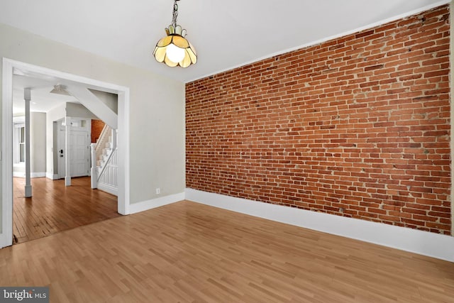 1223 Euclid St NW, Washington, DC 20009 - unfurnished room with wood finished floors, brick wall, and stairway
