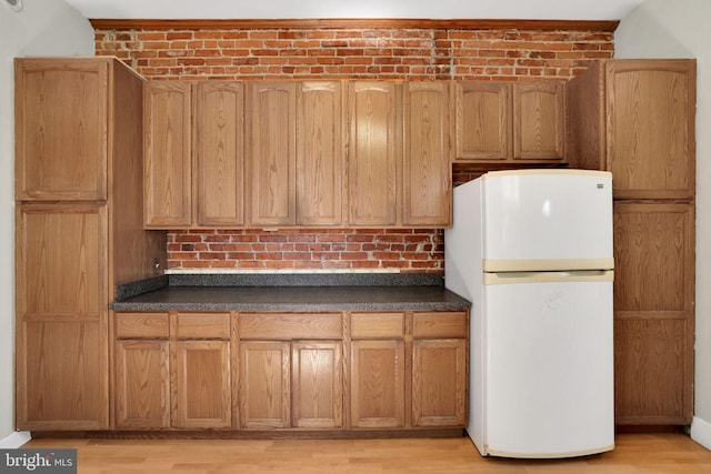 1223 Euclid St NW, Washington, DC 20009 - kitchen featuring freestanding refrigerator, dark countertops, light wood-type flooring, and brown cabinets