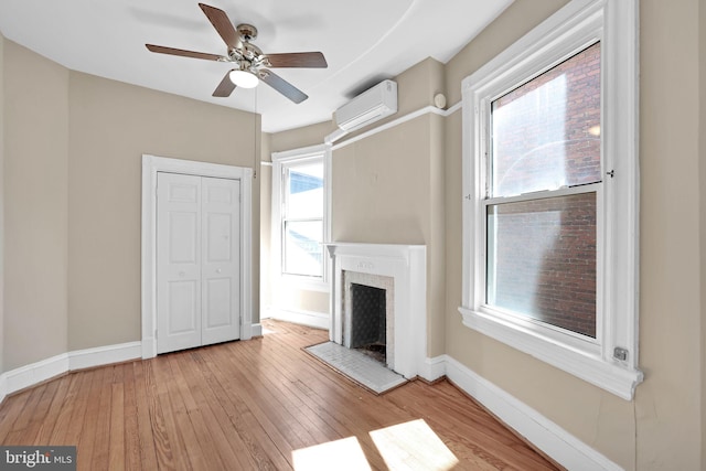 1223 Euclid St NW, Washington, DC 20009 - unfurnished living room with a wall mounted air conditioner, ceiling fan, light wood-style flooring, and a fireplace