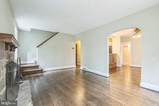 2504 Parkview Rd, Baltimore, MD 21207 - unfurnished living room featuring arched walkways, stairs, wood finished floors, a ceiling fan, and a fireplace