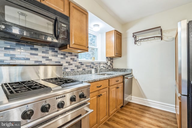 2504 Parkview Rd, Baltimore, MD 21207 - kitchen with appliances with stainless steel finishes, light wood finished floors, light stone counters, backsplash, and brown cabinets
